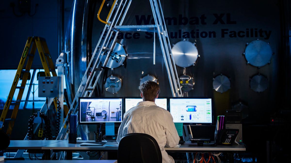 A researcher studying an array of screens at the Wombat XL Space Simulation Facility at ANU