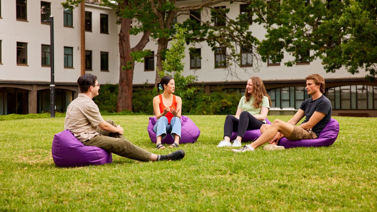 ANU students sitting on purple bean bags on campus in discussion. 