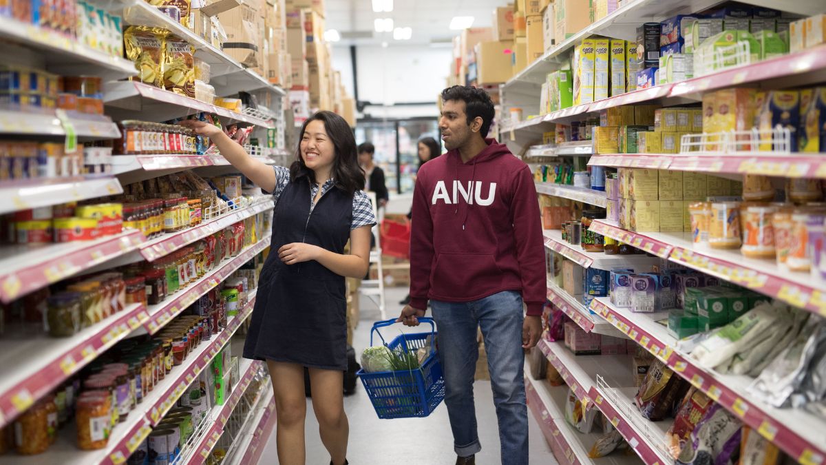Two ANU students walking down the aisles of the Daily Market to shop for budget-friendly groceries