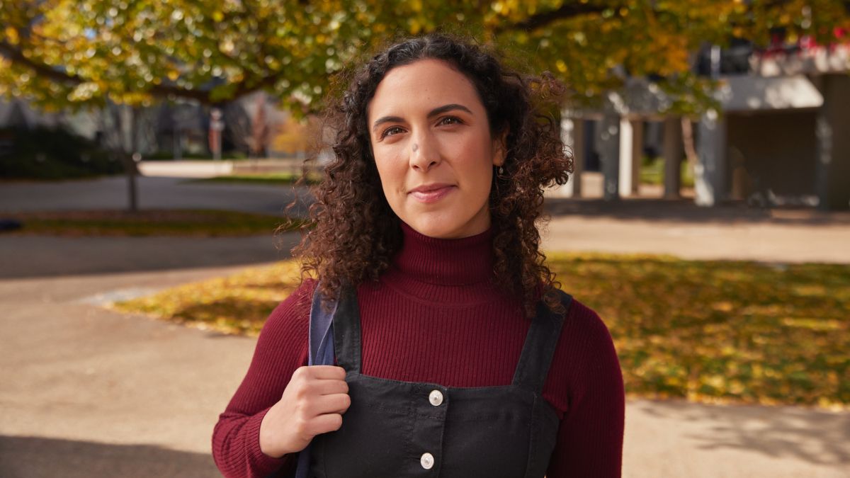 ANU student holding the strap of her bookbag in one hand and smiling. 