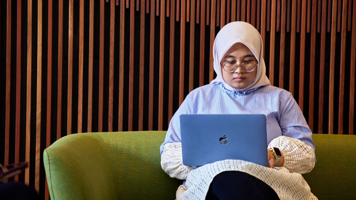 Female ANU student typing an assignment using academic writing on her laptop on campus.