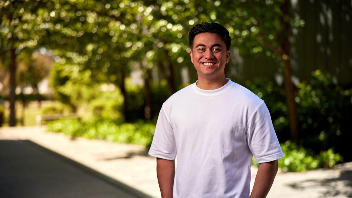 Male ANU student smiling at the camera on the ANU campus in Canberra. 