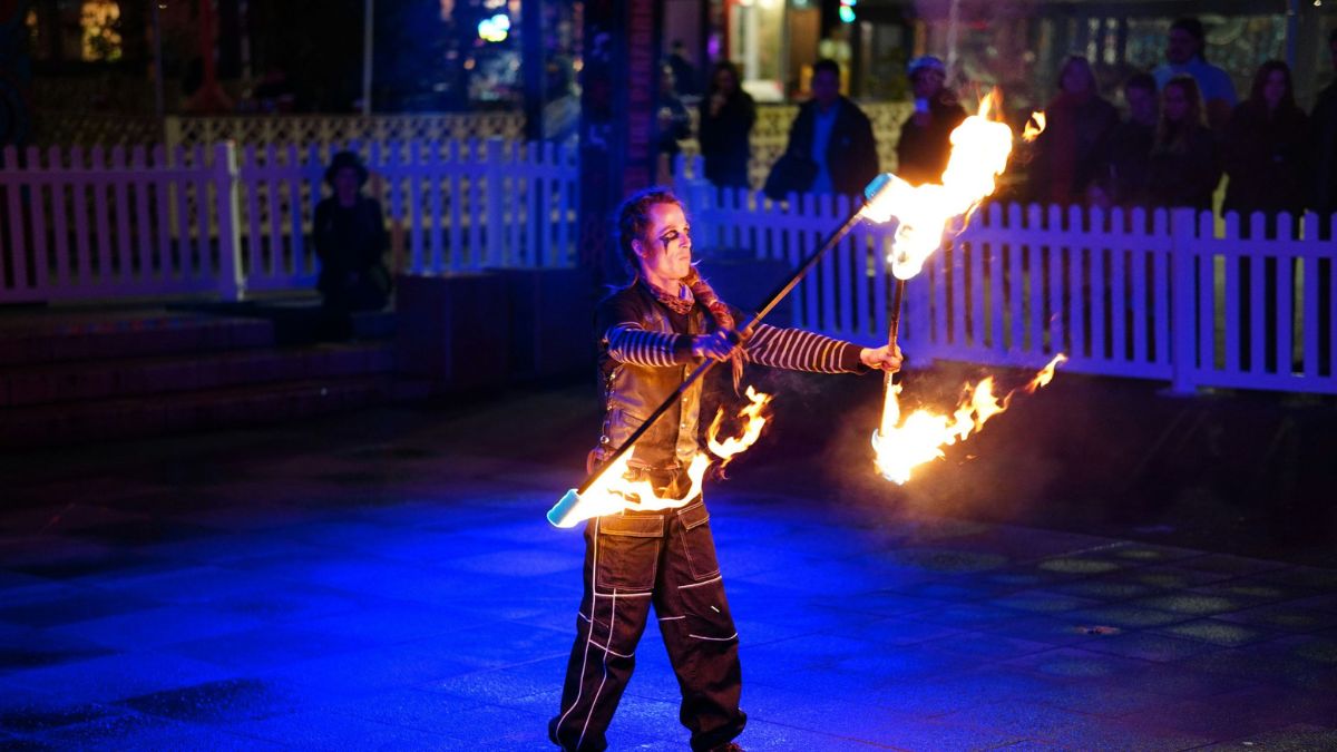 A street performer fire throwing at a Canberra festival at night. 