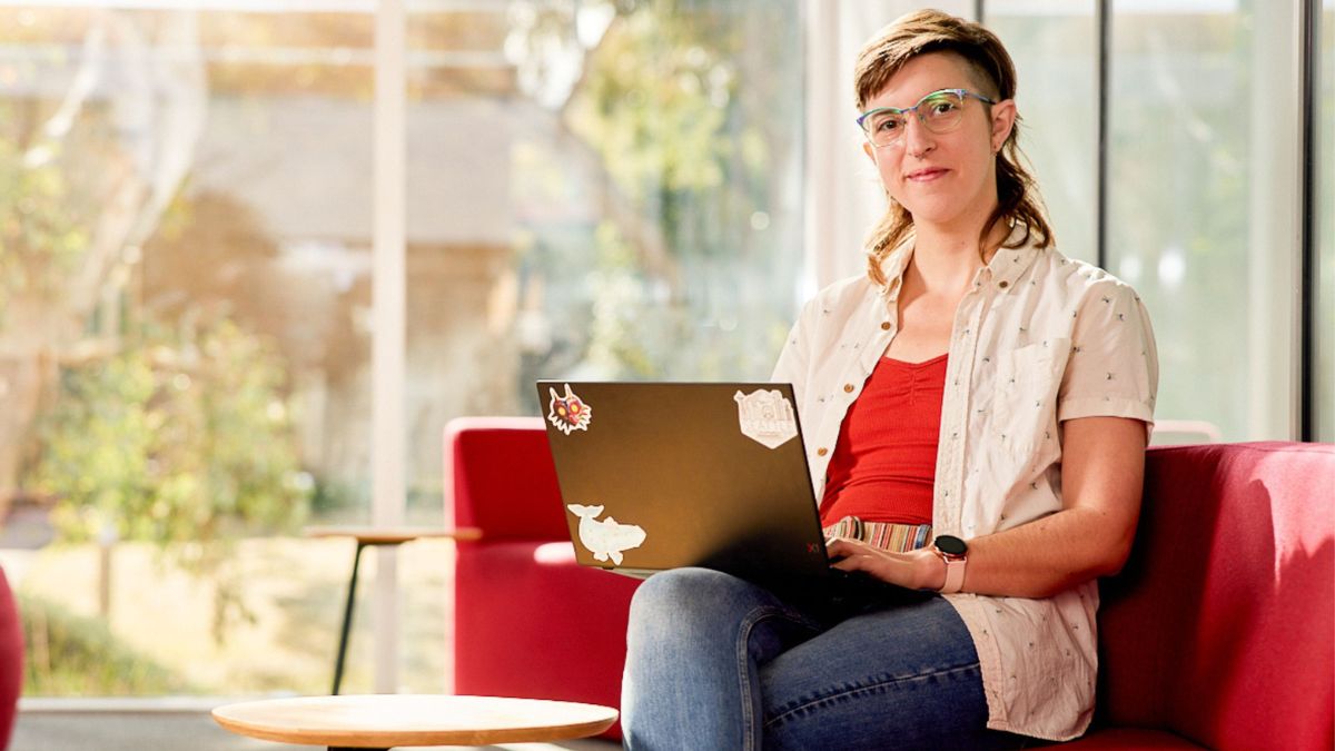 An ANU student studies within a building on campus with a laptop.