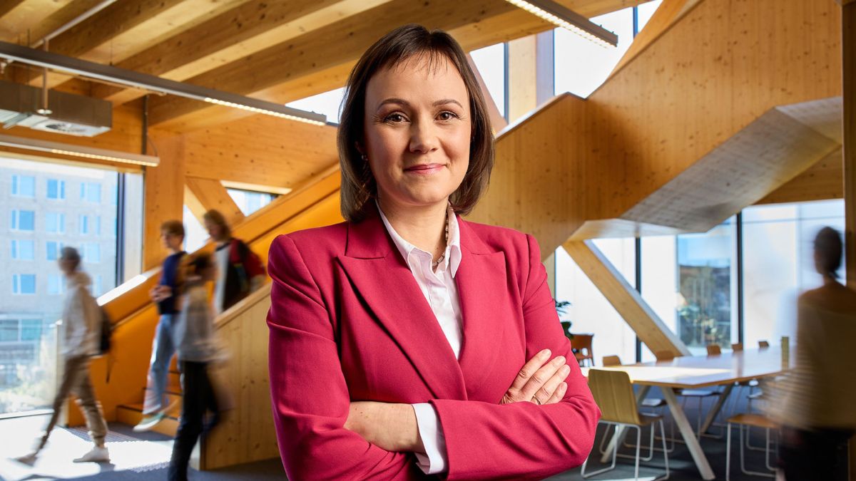 Associate Professor Anna Olsen stands in front of the camera with arms crossed, shot within the Marie Reay Teaching Centre.