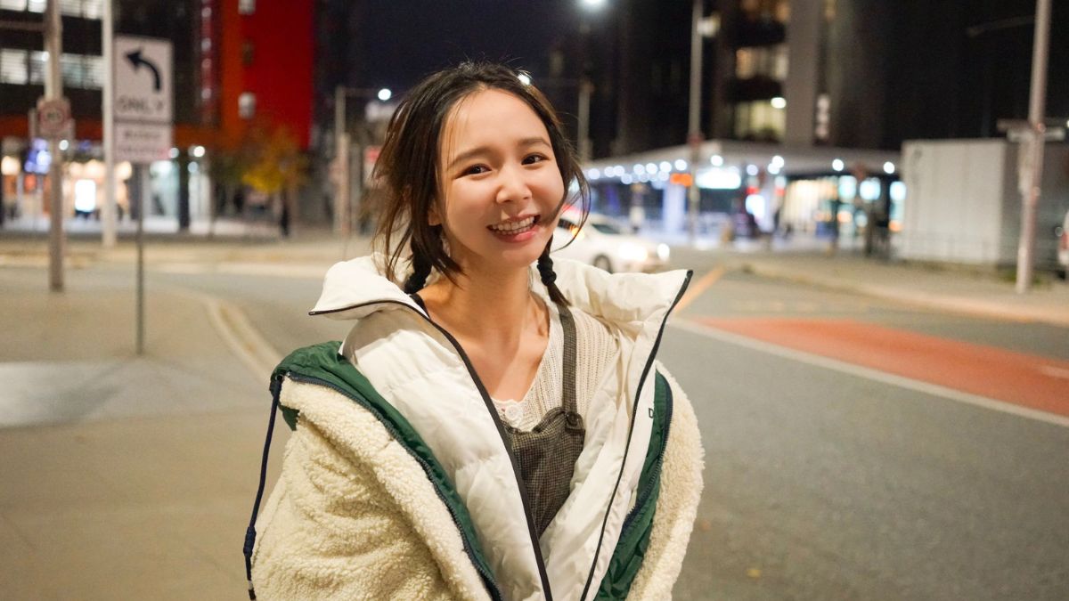 Yixi smiles at the camera with the Canberra nightlife setting the scene behind her.