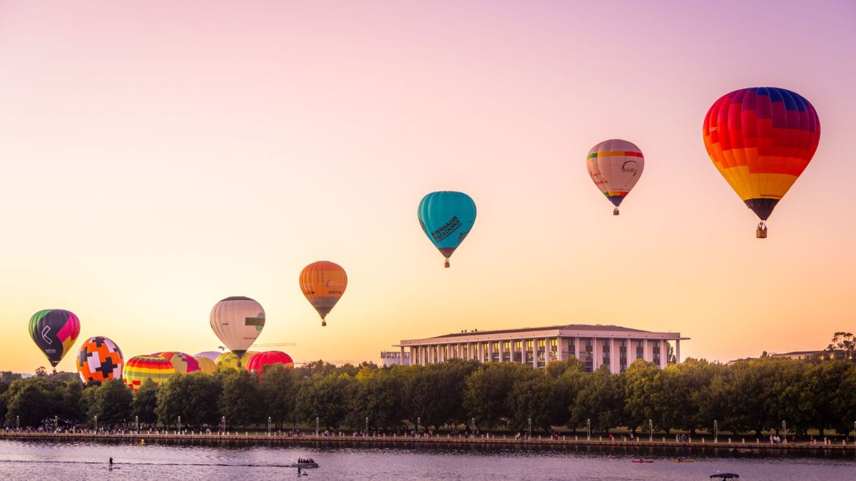 Hot air balloons float over a Canberra sunrise and the National Library of Australia.