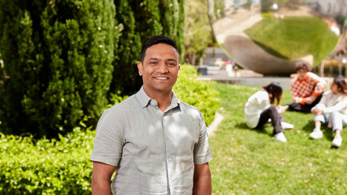 ANU postgraduate student stands in front of the Una Ball on the ANU campus.