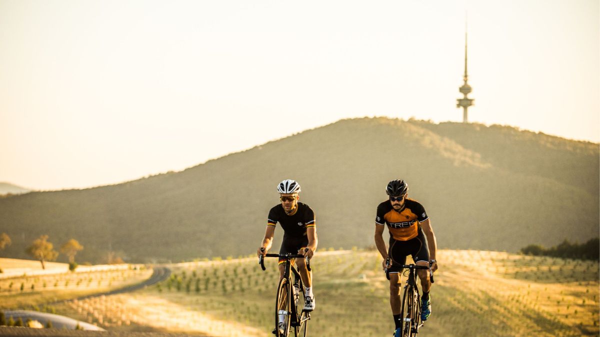 Two bike riders ride up hill at the National Arboretum in Canberra