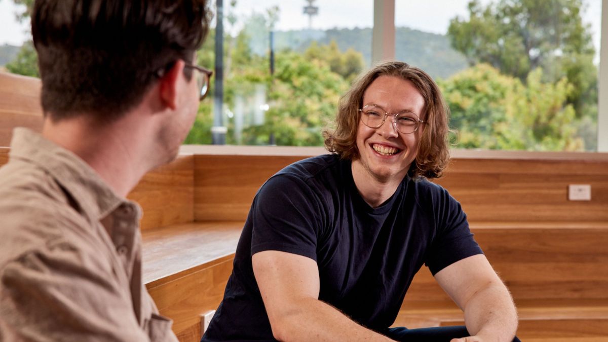 Two ANU postgraduate students sit in a learning space together on campus.