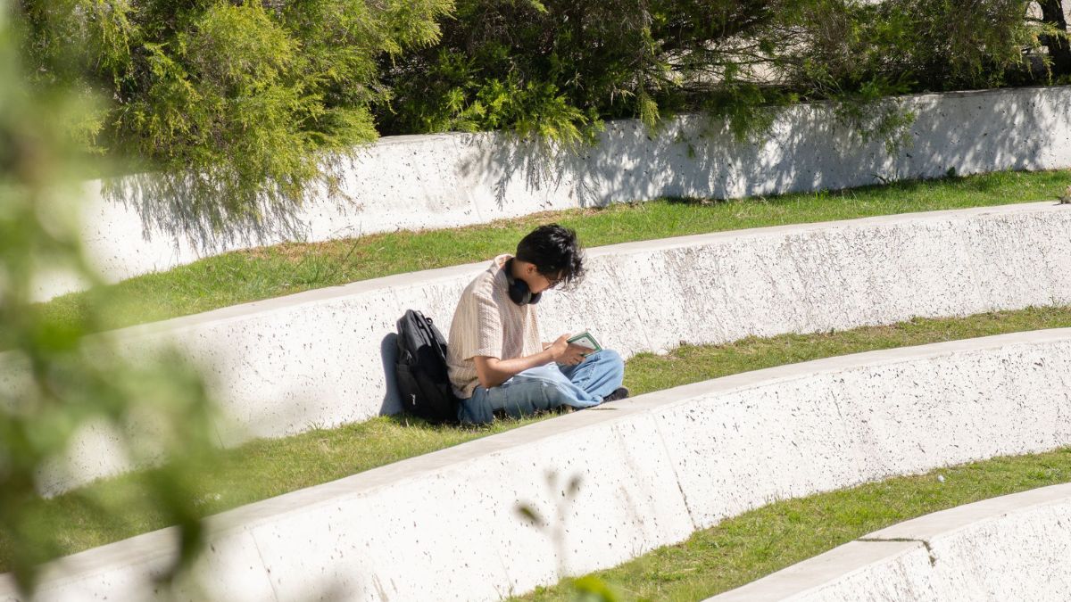 A student sits outside in the external amphitheatre of Kambri on the ANU campus.