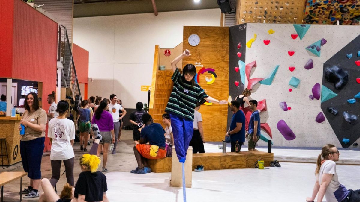 Blochaus Bouldering in Canberra with people gathering around the bouldering walls, while one person balances on a slackline in the centre of the space.