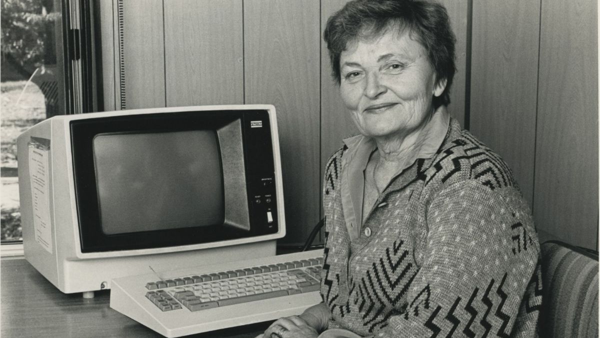 ANU Archives image of Skaidrite Darius sitting at a computer smiling at the camera.