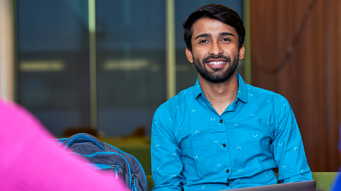 Person in blue button up shirt smiling towards camera