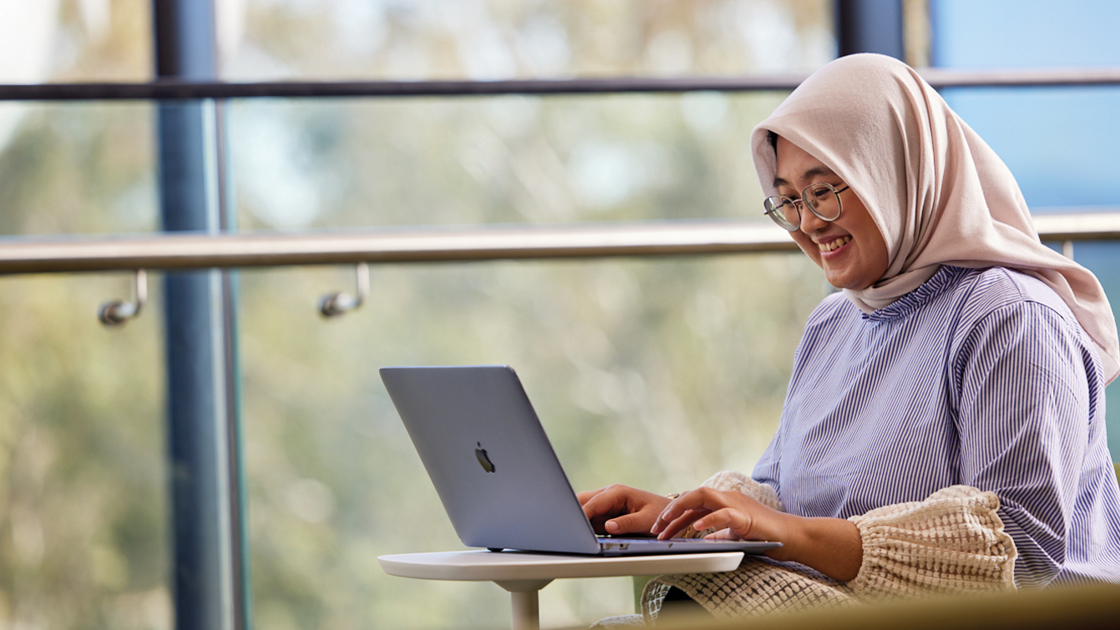 Person sitting down smiling at laptop