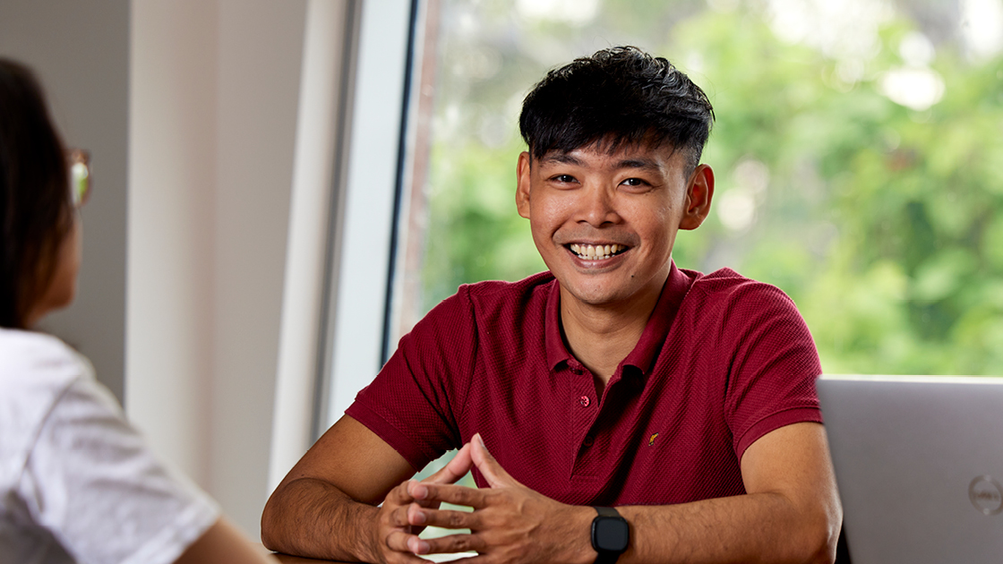 Person sitting down smiling towards camera
